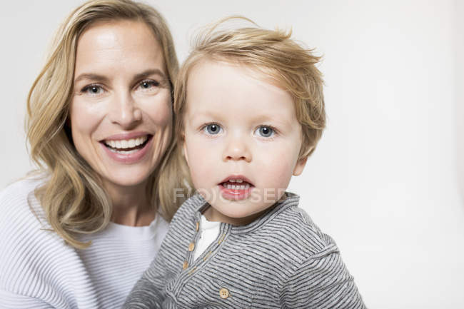 Портрет матері і сина на білому тлі, посміхаючись — стокове фото