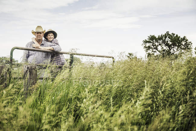 Retrato de granjero y nieto adolescente abrazándose en la puerta de la granja - foto de stock