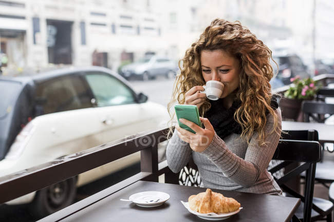 Жінка в кафе за допомогою смартфона пити кафе, Мілан, Італія — стокове фото