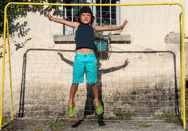 Niño en el fútbol gol saltando en el aire - foto de stock