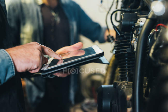 Two mature men, working in garage, using digital tablet, close-up — Stock Photo