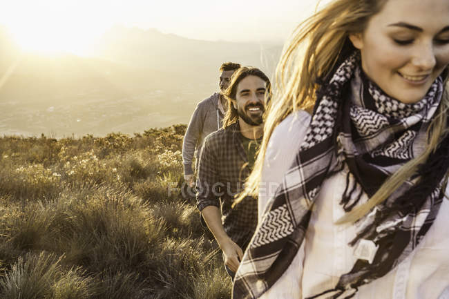 Des amis marchant sur les prairies souriant — Photo de stock