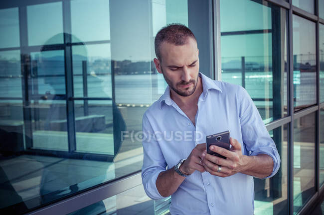 Бизнесмен за пределами офиса смс на смартфоне, Кальяри, Сардиния, Италия — стоковое фото