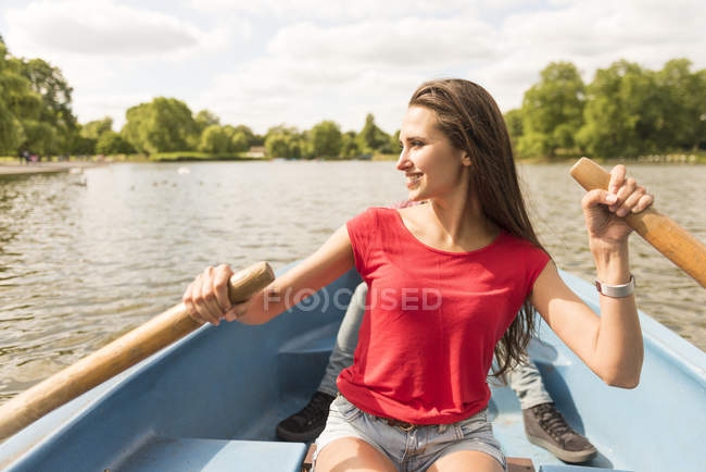 Young woman and boyfriend in rowing boat in park — Stock Photo