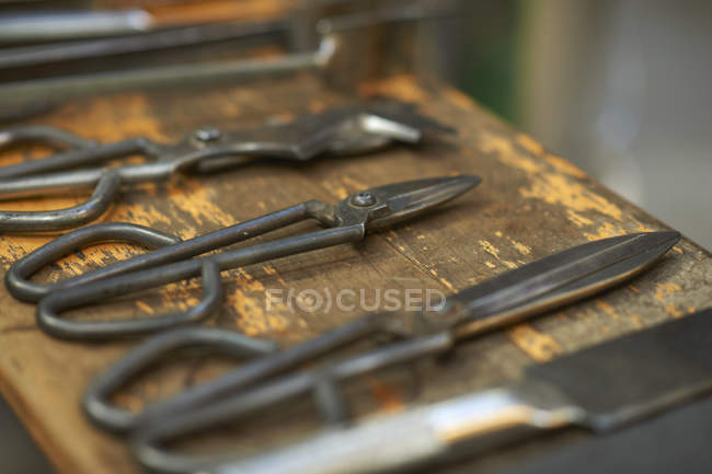 Close up de ferramentas manuais de sopradores de vidro colocados em uma fileira na superfície de madeira rasgada — Fotografia de Stock