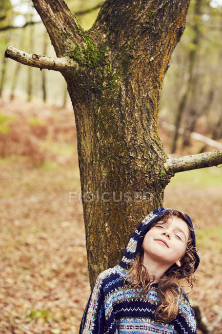Jovencita, apoyada en el árbol, los ojos cerrados - foto de stock