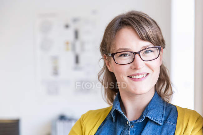 Портрет молодої жінки в окулярах дивиться на камеру посміхаючись — стокове фото