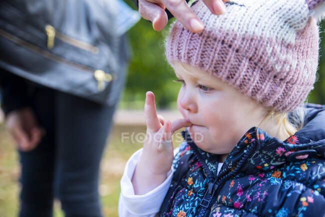 Female toddler with finger in her mouth in park — Stock Photo