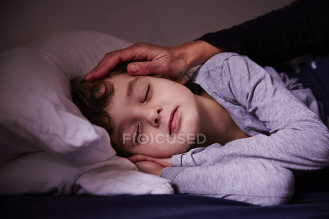 Madri mano accarezzando dormire ragazzo — Foto stock
