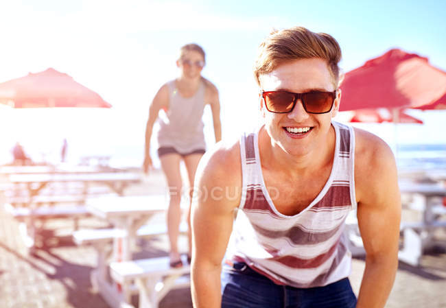 Ritratto di uomo che indossa occhiali da sole guardando la macchina fotografica sorridente — Foto stock