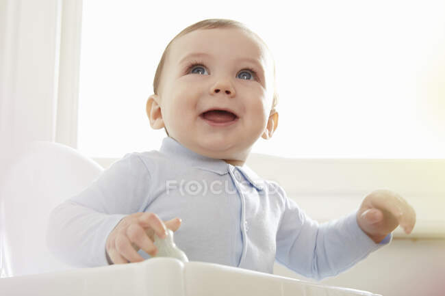 Enfant garçon aux yeux bleus sur chaise haute — Photo de stock