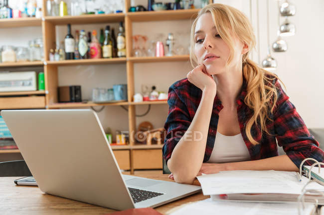 Woman with laptop looking at paperwork — Stock Photo