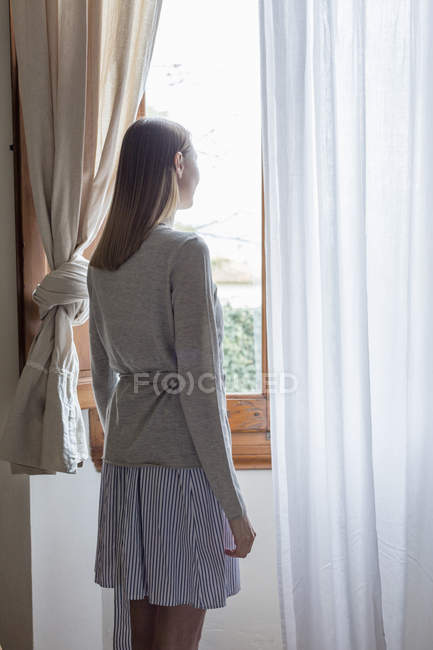 Вид сзади на женщину, выглядывающую из окна — стоковое фото