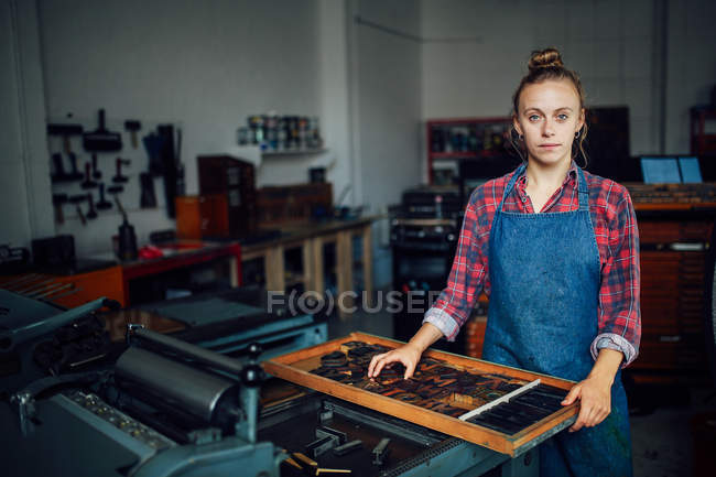 Porträt einer jungen Kunsthandwerkerin neben Tablett mit Buchstaben in Druckereiwerkstatt — Stockfoto