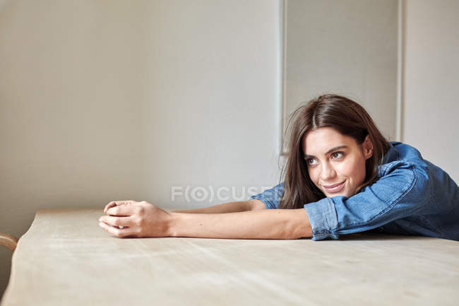 Портрет красива молода жінка спершись на обідній стіл — стокове фото
