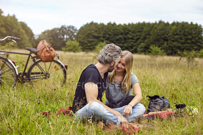 Casal romântico sentado em cobertor de piquenique no campo rural — Fotografia de Stock