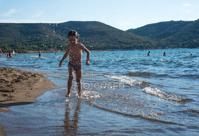 Ragazzo che remava in onde lappate sulla costa, Italia — Foto stock
