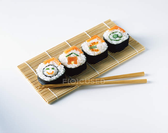 Salmon sushi on placemats with wooden chopsticks — Stock Photo