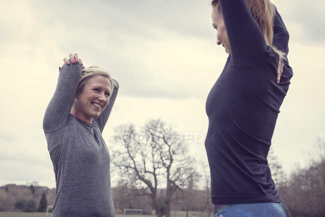 Women face to face, hands behind head stretching — Stock Photo
