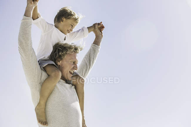Father giving son piggyback on beach — Stock Photo