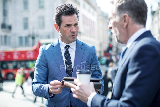 Empresarios en la calle usando tableta digital, Londres, Reino Unido - foto de stock