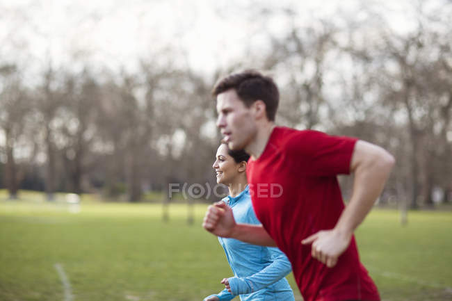 Young man and woman running together in park — Stock Photo