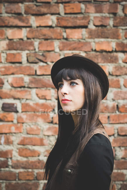 Young woman in front of brick wall — Stock Photo