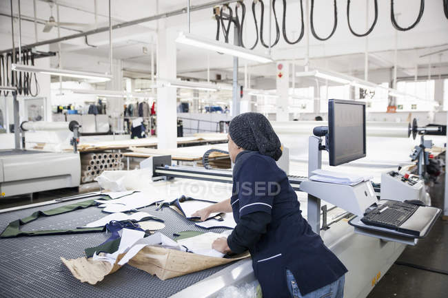 Factory worker removing cut textile pattern from pattern cutting machine in clothing factory — Stock Photo