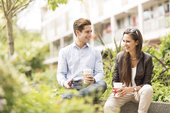Young businessman and woman talking in city park — Stock Photo