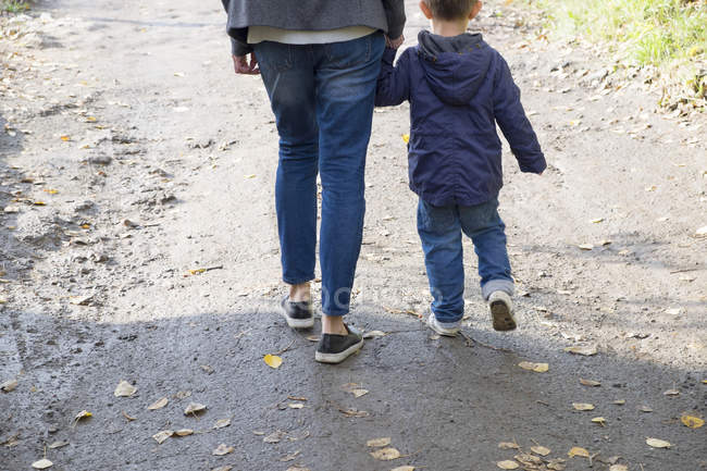 Rear view of woman and son strolling along dirt track — Stock Photo