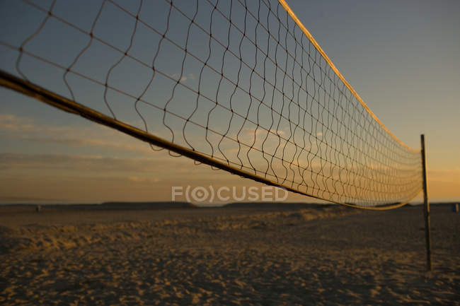 Beach volleyball net with sunset sky — Stock Photo