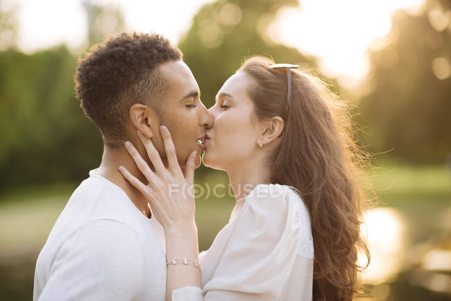 Вид сбоку на целующуюся молодую пару — стоковое фото