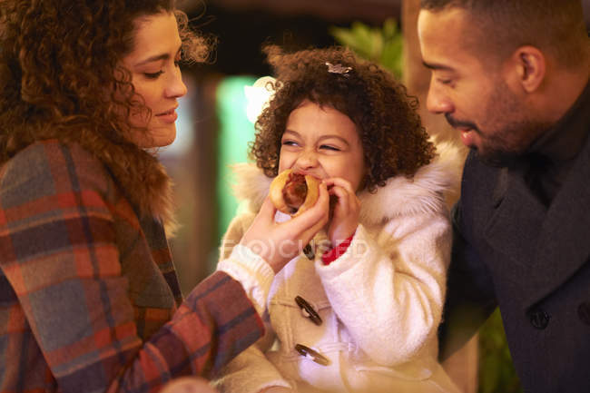 Mother and father feeding daughter hot dog — Stock Photo