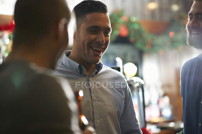 Young man in public house with friends smiling — Stock Photo