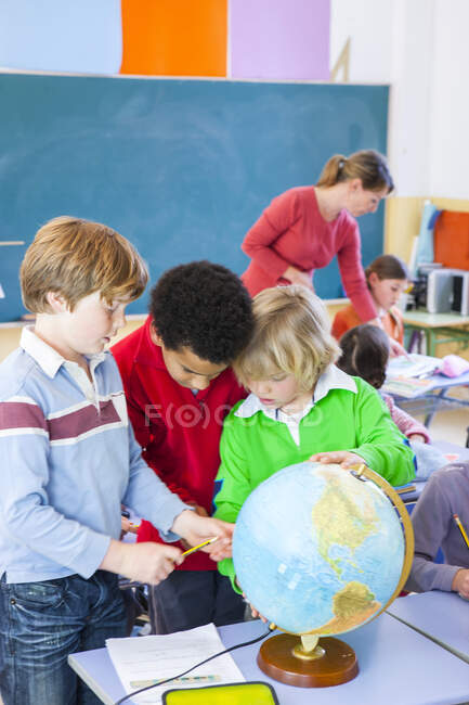 Primary schoolboys looking at globe in classroom — Stock Photo