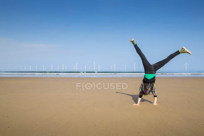 Mature woman doing cartwheel on Redcar beach, North Yorkshire, UK — Stock Photo