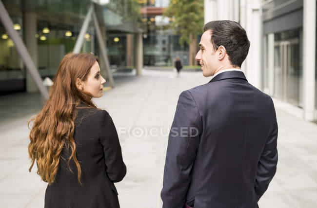 Rear view of businesspeople in city face to face smiling — Stock Photo