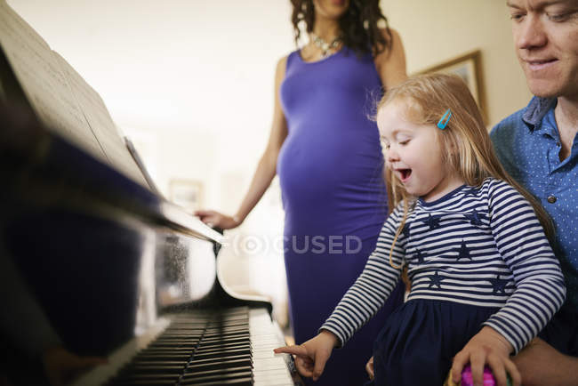 Genitori che insegnano alla figlia a suonare il pianoforte — Foto stock