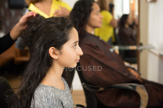 Chica y madre que tienen su peinado en el salón de belleza - foto de stock