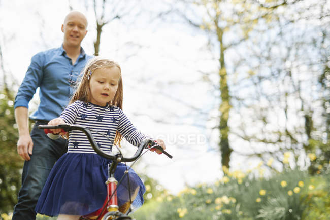 Pai ensinando filha a andar de bicicleta juntos — Fotografia de Stock