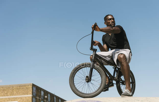 Jovem na bicicleta BMX olhando por cima de seu ombro no skatepark — Fotografia de Stock