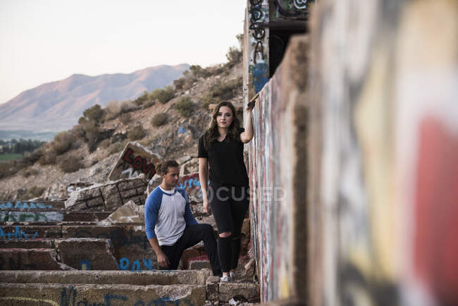 Молодой человек и женщина изучают стены граффити на разрушенной шахте — стоковое фото