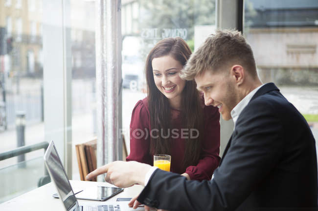 Businesswoman and businessman working with laptop in cafe — Stock Photo