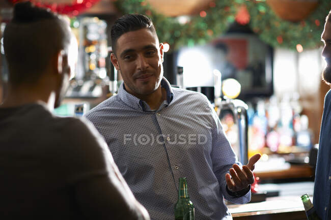 Man leaning against counter in public house talking to friend — Stock Photo