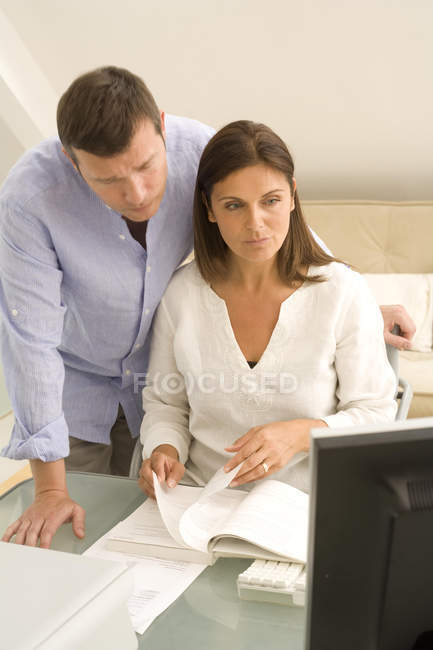 Casal maduro verificando contas no computador desktop em casa — Fotografia de Stock