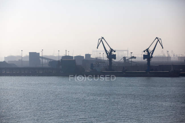 Vista a distanza di gru e container in porto — Foto stock