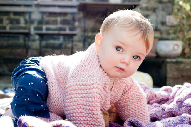 Portrait of baby girl crawling on knitted blanket in garden — Stock Photo