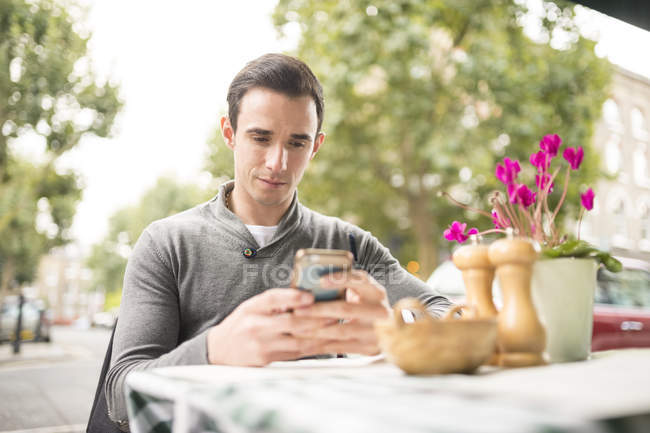 Man at pavement cafe looking at smartphone — Stock Photo