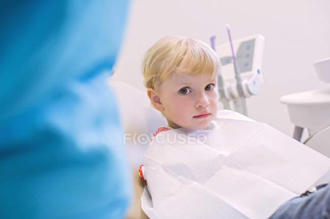 Fille dans une chaise de dentiste regardant caméra — Photo de stock