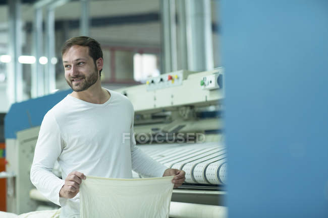 Homem na lavandaria usando a máquina de passar roupa — Fotografia de Stock